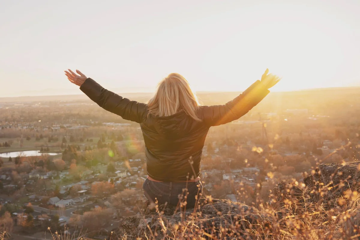 Woman standing outdoors with arms open to the sky